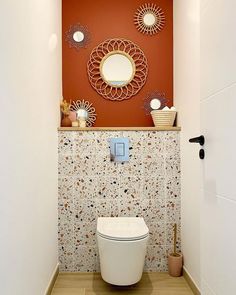 a white toilet sitting in a bathroom next to a wall with decorative mirrors on it