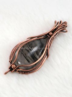 a wire wrapped pendant with a black stone in the center on a white furnishing