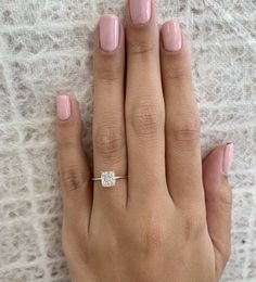 a woman's hand with pink nail polish and a diamond ring