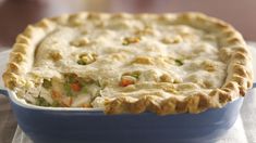 a chicken pot pie in a blue casserole dish on a white table cloth