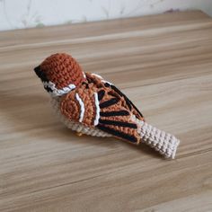 a crocheted bird sitting on top of a wooden table