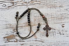 a rosary with a cross on it sitting on top of a wooden table in front of a white painted wall