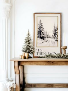 a christmas mantle with pine trees, candles and a framed holiday card on the mantle