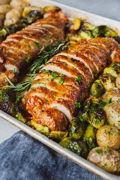 a pan filled with meat and vegetables on top of a blue table cloth next to potatoes