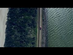 an aerial view of a car driving down the road next to the beach and water