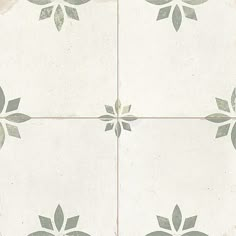 a white and gray tiled floor with flower designs on the tile, as well as an image of leaves