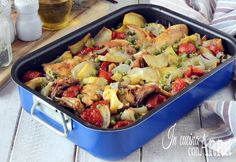 a blue casserole dish filled with meat, vegetables and cheese on a wooden table