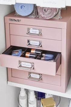 a pink file cabinet filled with lots of crafting supplies on top of a white shelf