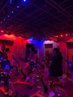 there are many people riding bikes in the room with red lights on their walls and floor