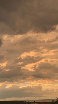 a plane flying in the sky with clouds above it and an airplane on the ground