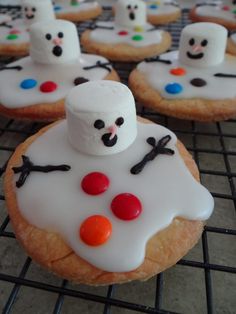 frosted cookies with marshmallows and snowmen on them sitting on a cooling rack