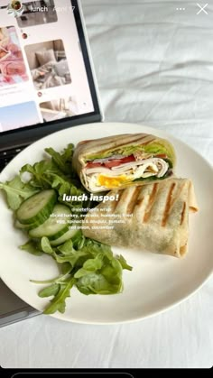 a white plate topped with a sandwich next to a laptop