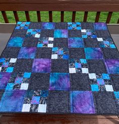 a blue and purple quilt sitting on top of a wooden bench