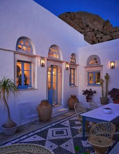 an outdoor dining area with potted plants and wicker chairs at the end of the patio