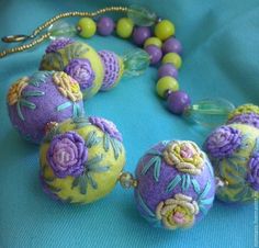 some beads are laying on a blue surface and there is a necklace made out of balls with flowers