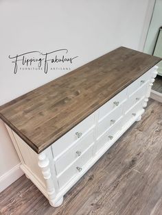 a white dresser with wood top and drawers in a room that has hardwood flooring