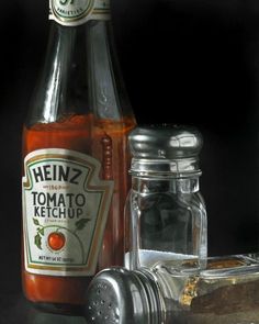 a bottle of tomato ketchup sitting next to a glass jar filled with something