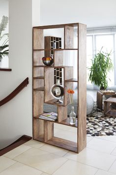 an open bookcase in the corner of a living room next to a stair case