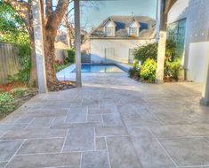 an empty patio with a pool in the back ground and trees on either side of it