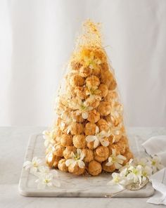 a small christmas tree made out of cookies on a white surface with flowers around it