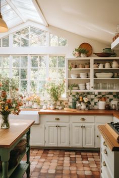 a kitchen filled with lots of counter top space and flowers in vases on the windowsill