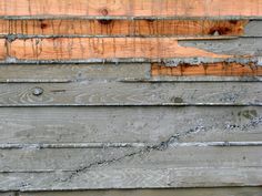 an old wooden wall with peeling paint and chipping on the wood paneling that has been stripped off