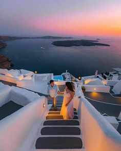 the bride and groom are walking down the stairs to their destination at sunset in oia