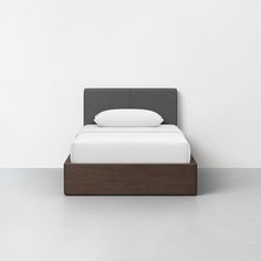 a bed that is made up and sitting in the middle of a room with white walls