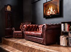 a brown leather couch sitting on top of a wooden floor next to a book shelf