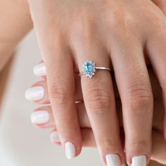 a woman's hand with white nails and a blue diamond ring on it,