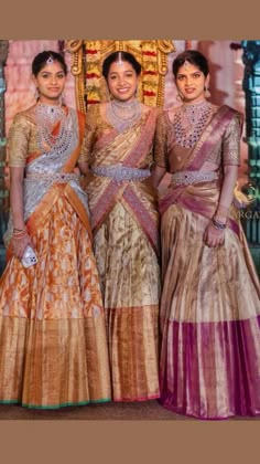 three women standing next to each other wearing different colored dresses and jewelry on their heads