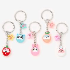 four keychains with different designs on them, one has an apple and the other has