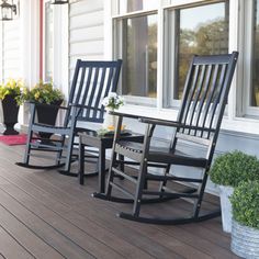 three rocking chairs on a porch with potted plants