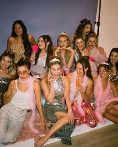 a group of women posing for a photo in front of a wall with pink and silver decorations