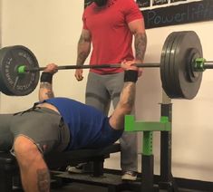 a man is lifting a barbell while another man watches