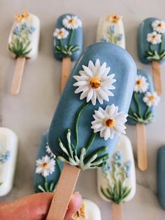 a hand holding a popsicle decorated with daisies