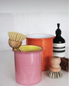 three different types of brushes and containers on a table with one brush in the cup