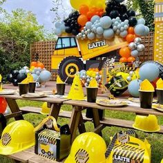 a construction themed birthday party with yellow and black decorations, balloons and hats on the table