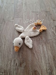 a crocheted bird laying on top of a wooden floor