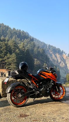 an orange and black motorcycle parked on the side of a road next to some trees