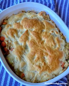 a casserole dish with meat and vegetables in it on a blue striped cloth