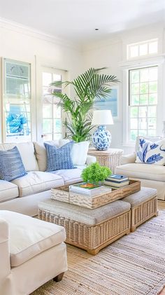 a living room filled with white furniture and blue and white pillows on the couches