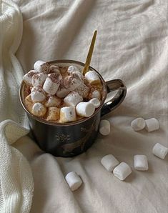 a cup filled with marshmallows on top of a bed