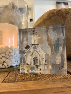 there is a candle and some rocks on the table with a church in the background