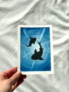 someone holding up a card with two dolphins on it