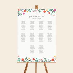 an easel with a seating chart on it and flowers around the top, in front of a white background