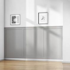 an empty room with two framed pictures on the wall and wood flooring in front of it