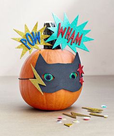 an orange pumpkin with a batman mask on it and some confetti sprinkles