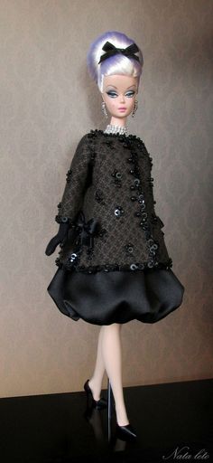 a doll is wearing a black dress and heels