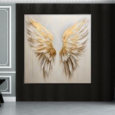 a large painting with gold wings on the wall next to a black and white chair